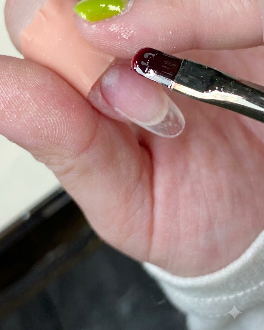 Gros plan dun pinceau à ongles appliquant une base transparente sur une capsule dongle transparente.