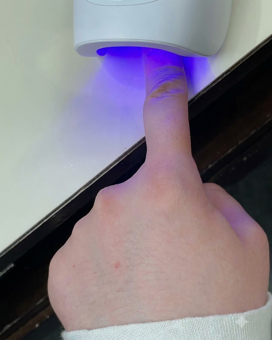 Un pinceau fin traçant le contour de la French avec du gel argenté.