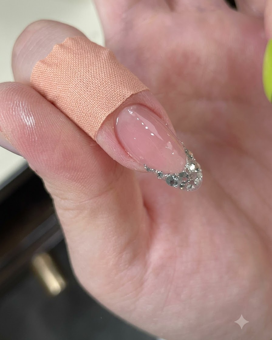 Un doigt nettoyé avec un pad, révélant une French en paillettes argentées texturées.