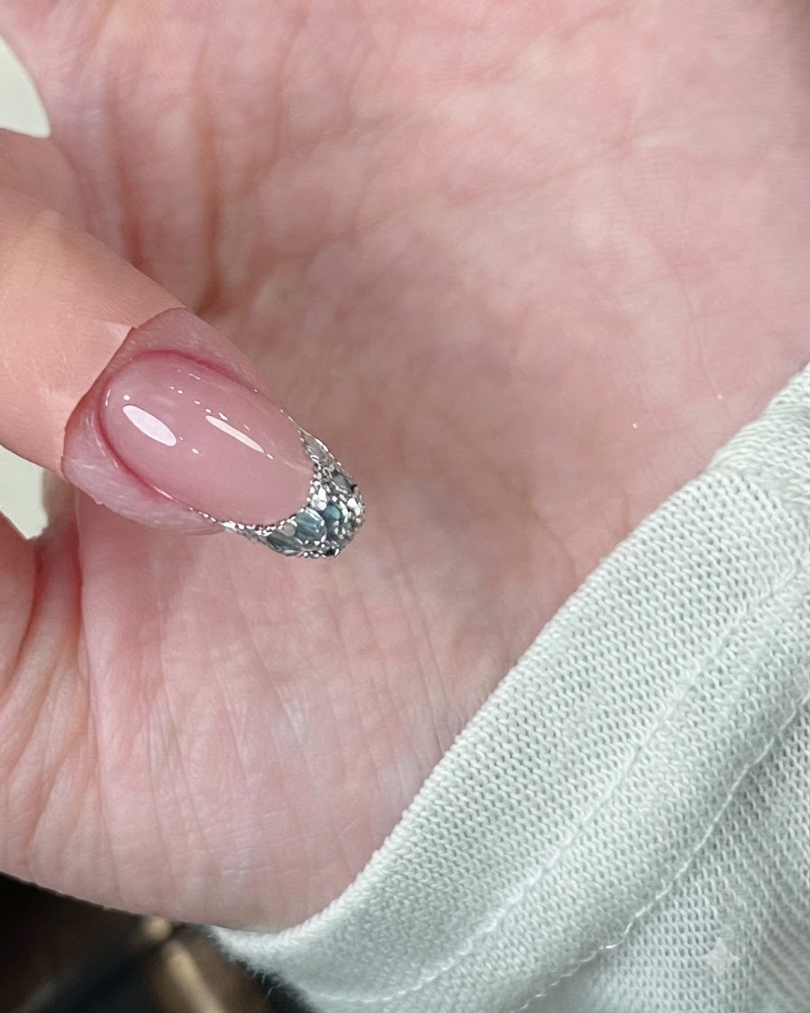 Une pince à épiler pinçant doucement les rebords dun ongle en gel sous une lampe.