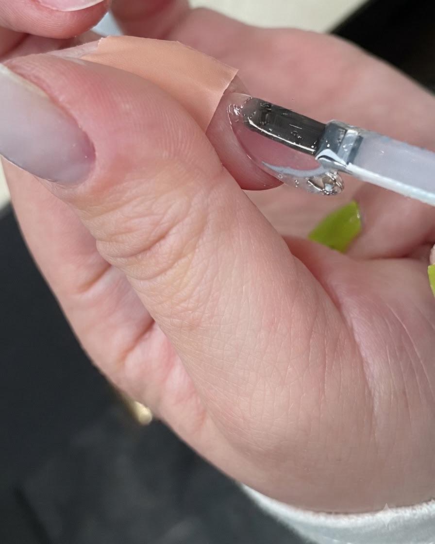 Une main catalysant la manucure finie à lintérieur dune lampe à ongles UV blanche compacte.