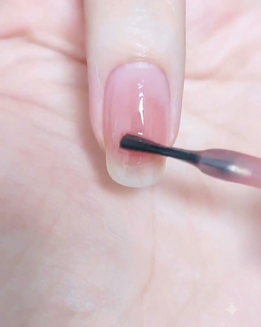 Un pinceau à ongle estompant délicatement le point central vers les bords de longle.