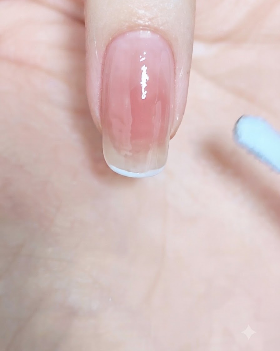 Gros plan sur une courbe de French bleu pastel dessinée le long du bord supérieur dun ongle.