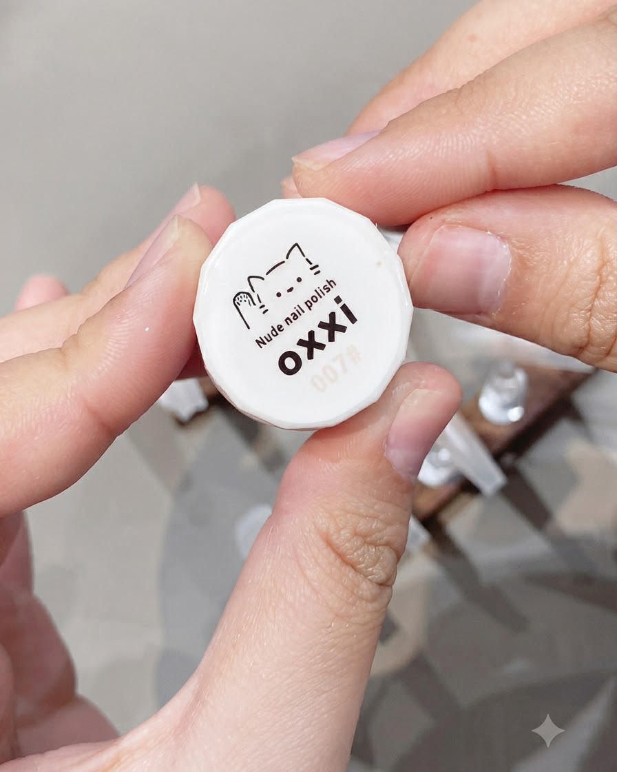 Une main tenant le bouchon de bouteille blanc du vernis à ongles nude Oxxai numéro 07.