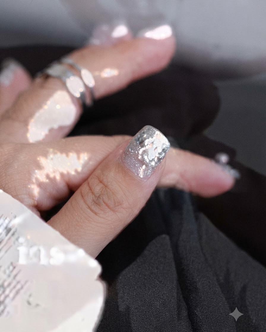 Gros plan dune main appliquant des traits de vernis gel blanc irréguliers sur un ongle à laide dun pinceau fin.