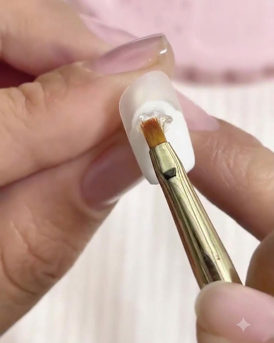 Un pinceau fin façonnant du gel de modelage transparent 3D en motifs de reliefs sur un ongle décoré.