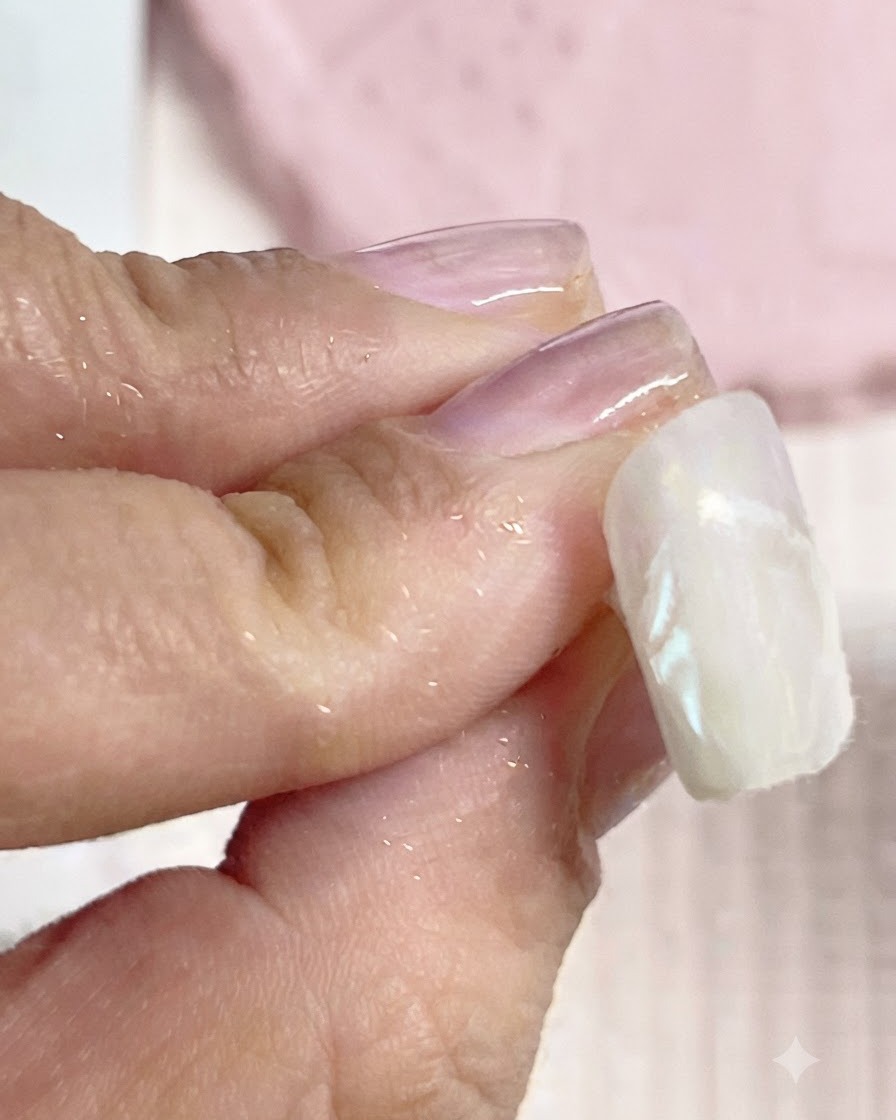 Une lingette nettoyante éliminant lexcès de poudre chrome sur les contours dun ongle terminé.