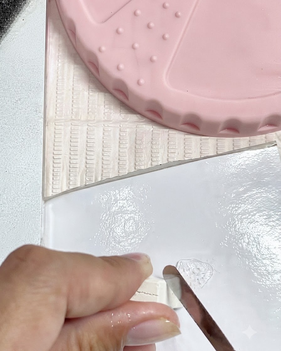 Un outil métallique coupant de petits morceaux dargile blanche sur une plaque de mélange propre.