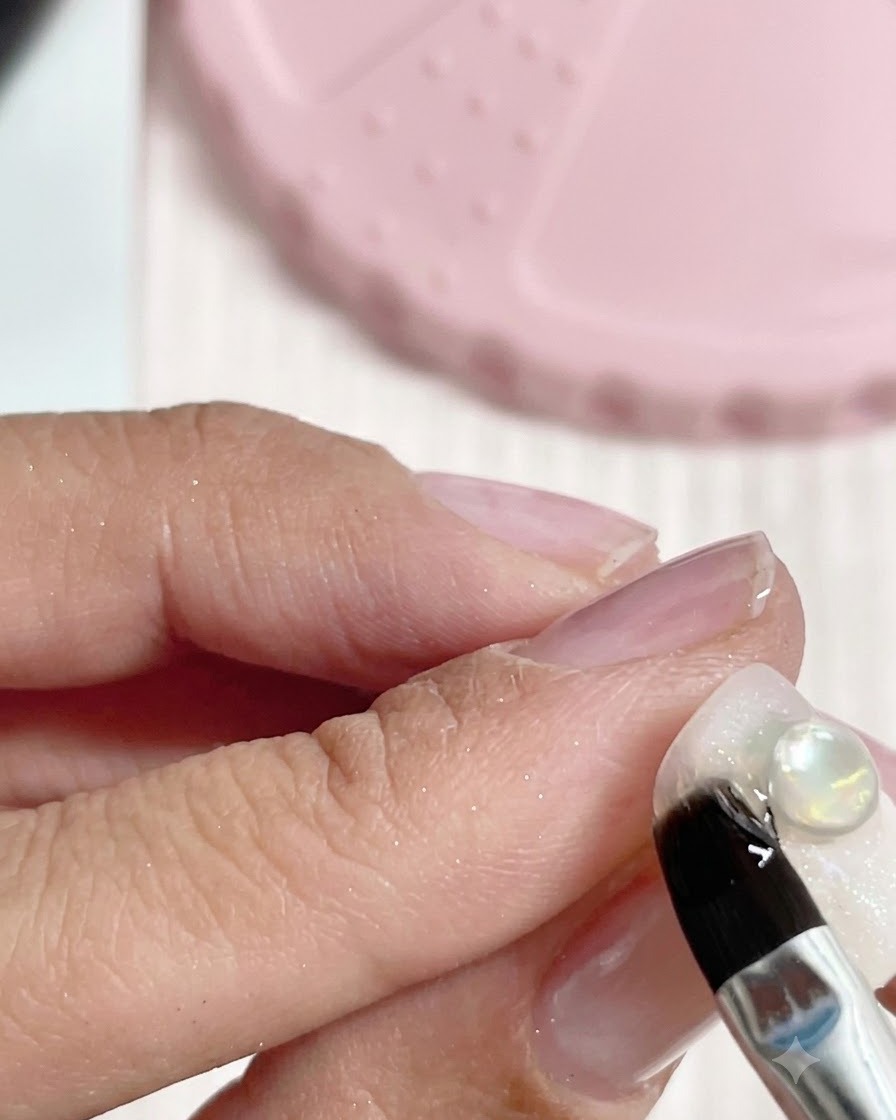 Un pinceau de détail appliquant une noisette transparente de gel dextension sur la base dun ongle décoré.