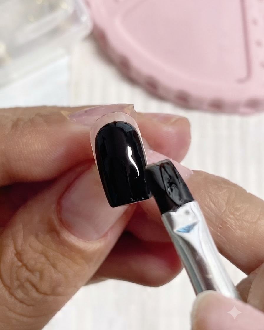 Un pinceau appliquant du gel de construction transparent sur une base dongle noire et blanche.
