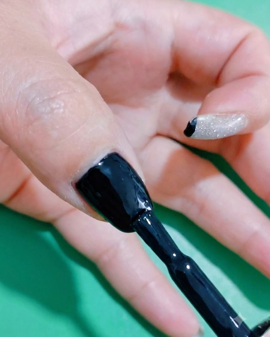 Un pinceau appliquant une couche supplémentaire de vernis gel noir pour assurer une saturation riche.