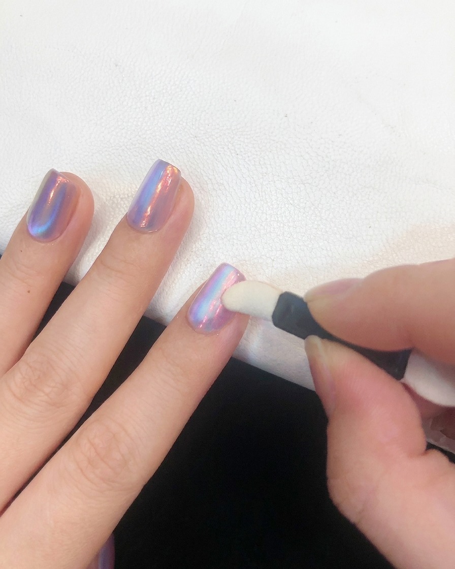 Un coton propre pressé en douceur sur un ongle poli au chrome pour fixer la poudre.