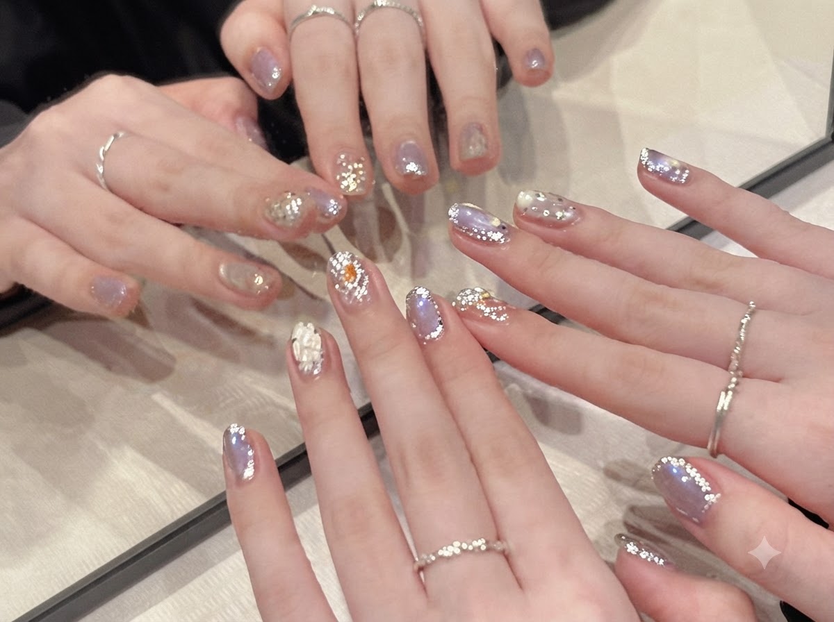 Vue rapprochée des mains délicatement inclinées sous une lumière douce, révélant leffet cat eye argenté scintillant sur des ongles pastel.