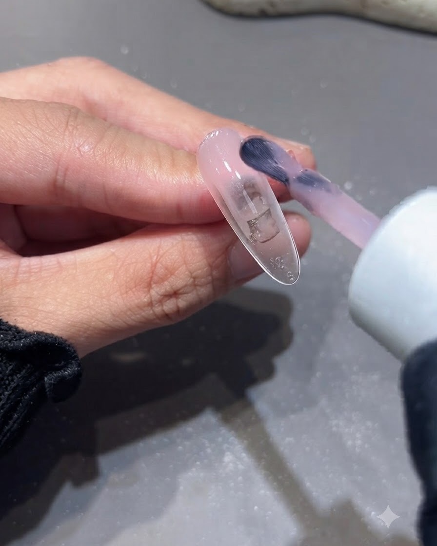 Un pinceau appliquant la deuxième couche de gel de base rose nude sur une extension dongle.
