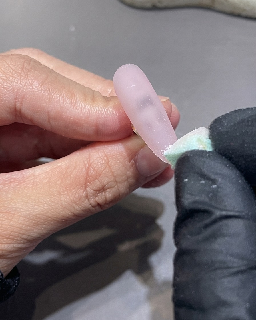 Une éponge tapotant verticalement vers le haut depuis le bout dun ongle pour estomper le gel blanc.