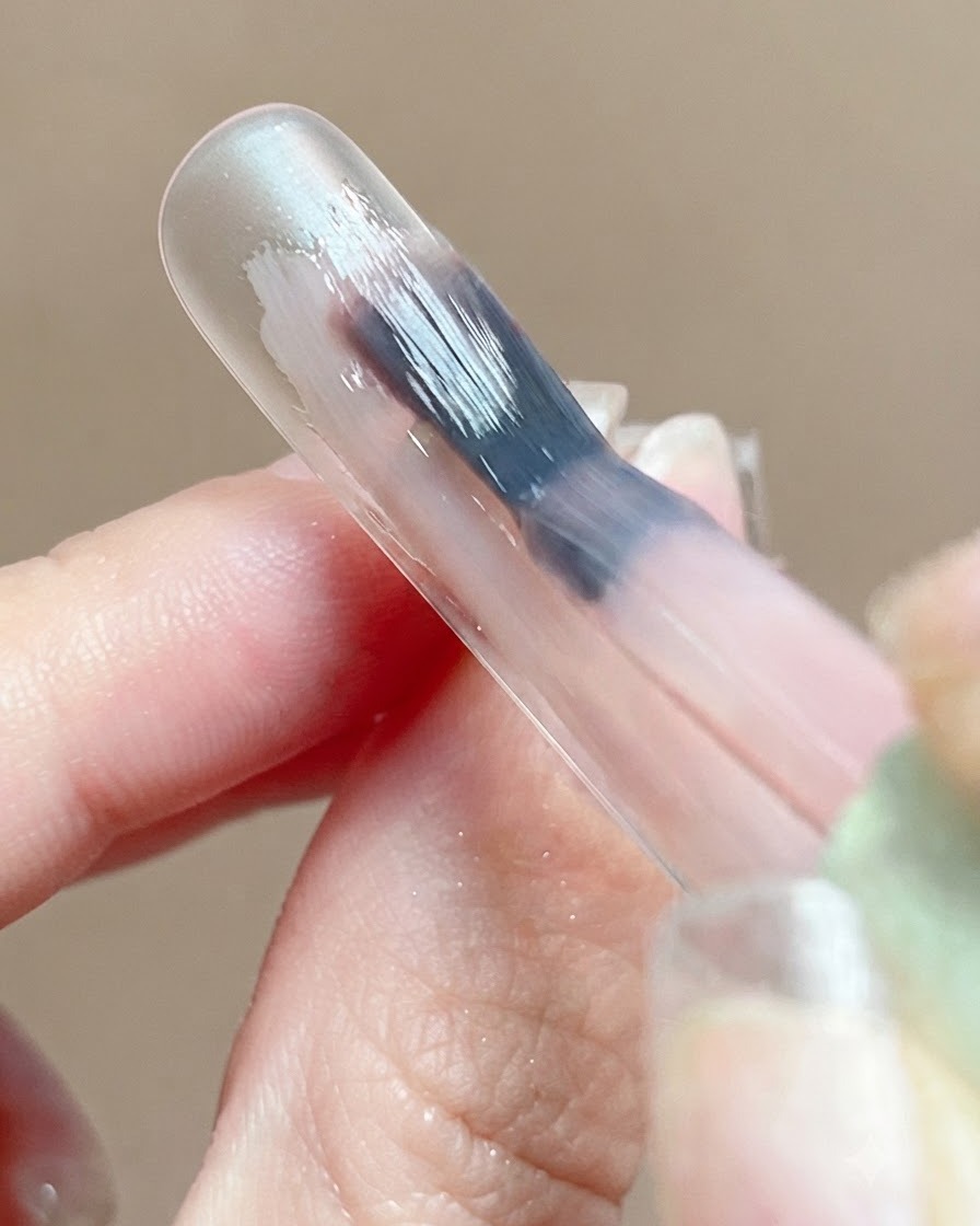 Gros plan dune base en gel rose reflétant la lumière en douceur sur la surface dun ongle pendant lauto-nivellement.