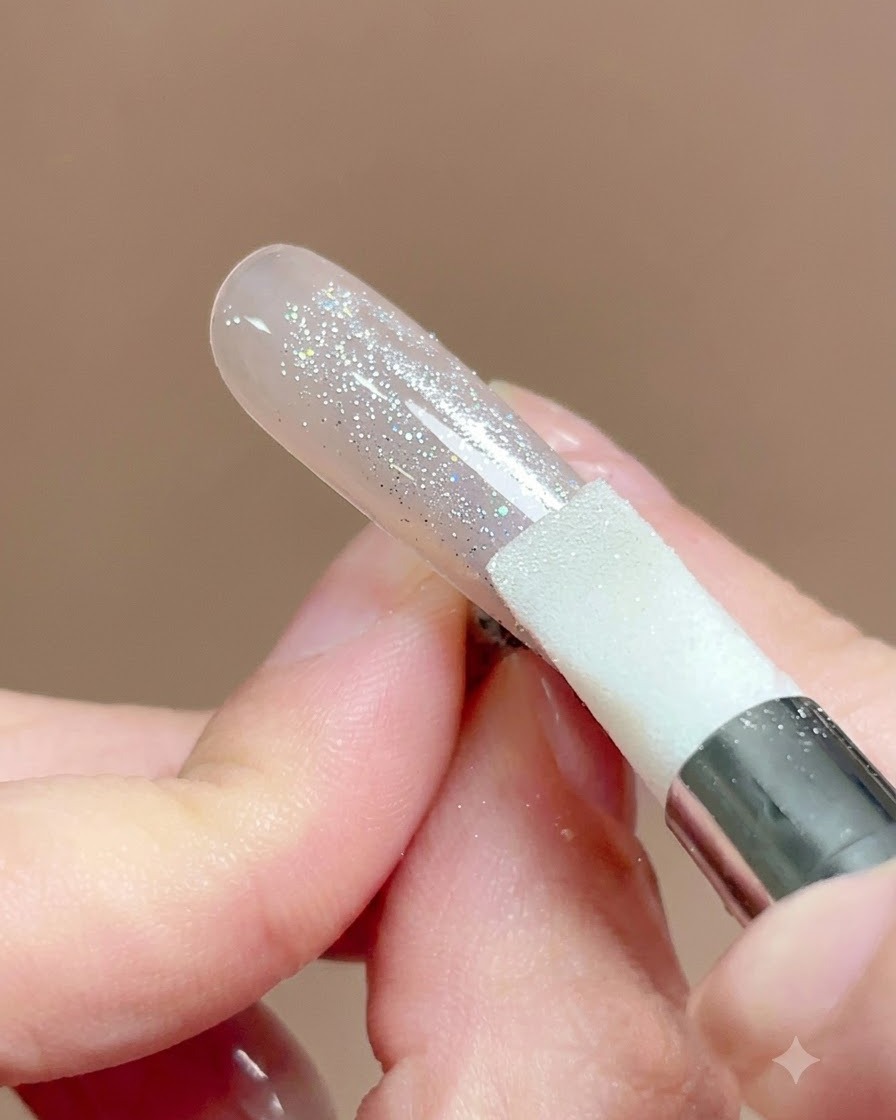 Un outil stylo en silicone pressé et frotté sur la surface dun ongle recouvert de poudre chrome.