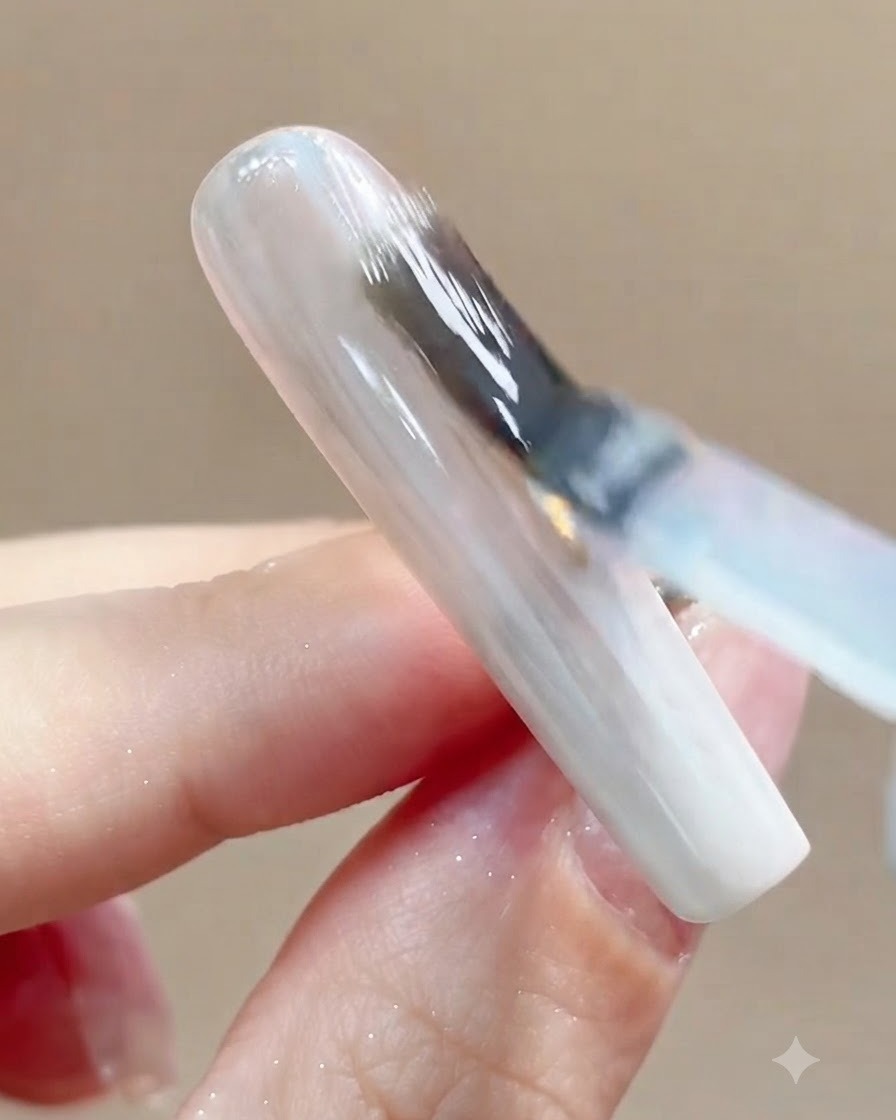 Vue rapprochée dun ongle placé sous une lampe de catalysation UV ou LED après lapplication de la couche de finition.