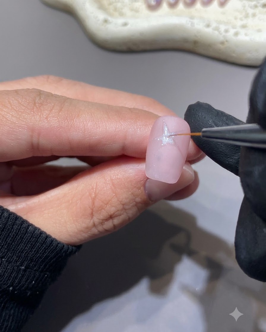 Un pinceau fin dessinant une forme détoile blanche sur une surface dongle rose.