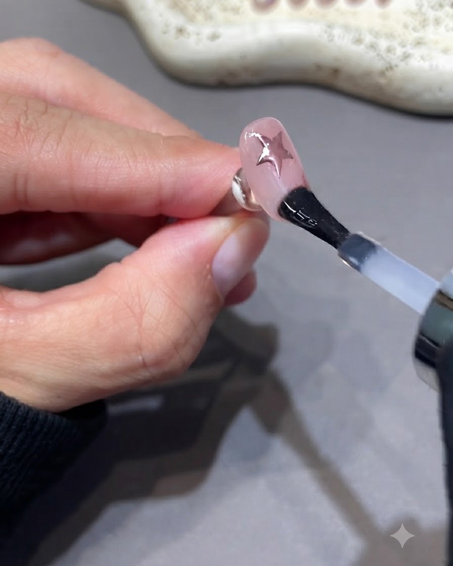 Un pinceau appliquant une couche supplémentaire de top coat de scellement sur un ongle manucuré.