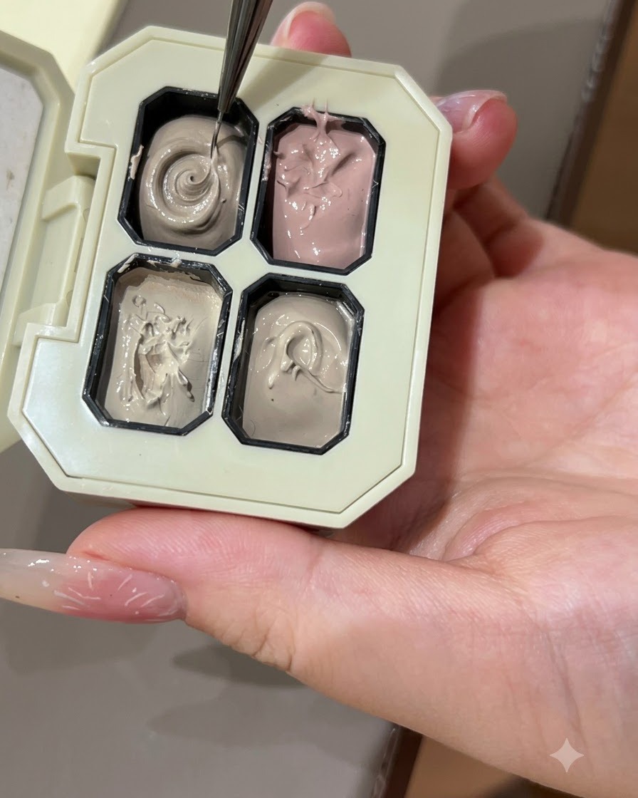 Un pinceau fin pour nail art prélevant du gel de couleur grise dans un compartiment dune palette.