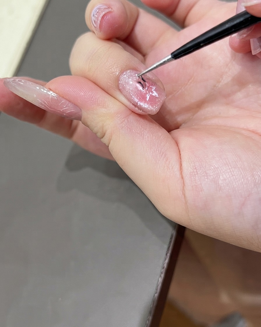Une paire de pinces fines retirant délicatement un autocollant dongle en forme détoile dun ongle manucuré en gel cat-eye brillant.