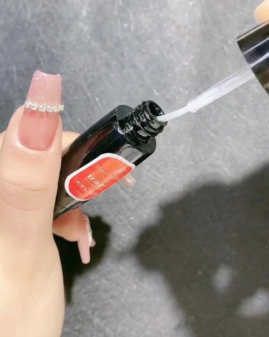Un flacon de gel de scellement transparent muni dun pinceau applicateur utilisé pour sécuriser les décorations dongles.