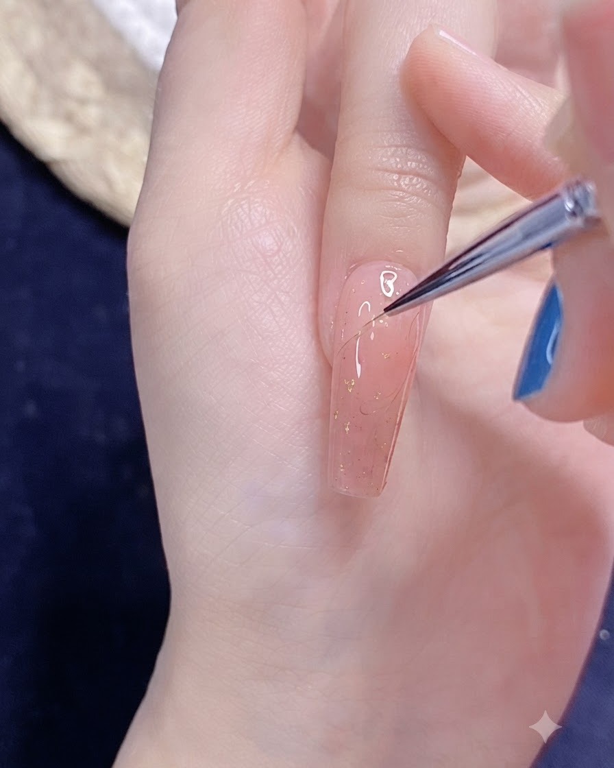 Un pinceau fin de nail art dessinant délicatement le contour dun demi-cœur en gel sur un ongle vernis en rose.