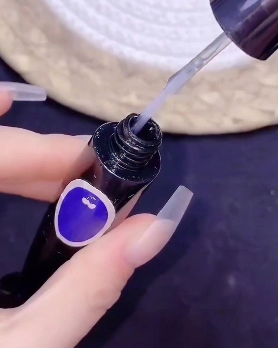 Un pinceau fin plongeant dans un flacon de top coat sans résidu lors dune pose de nail art.