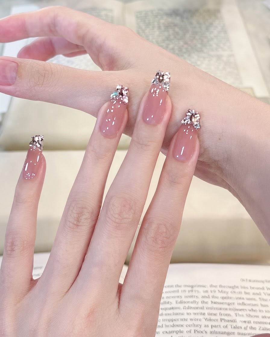 Vue panoramique fluide sur quatre doigts manucurés présentant une surface en gel translucide rose clair brillant.