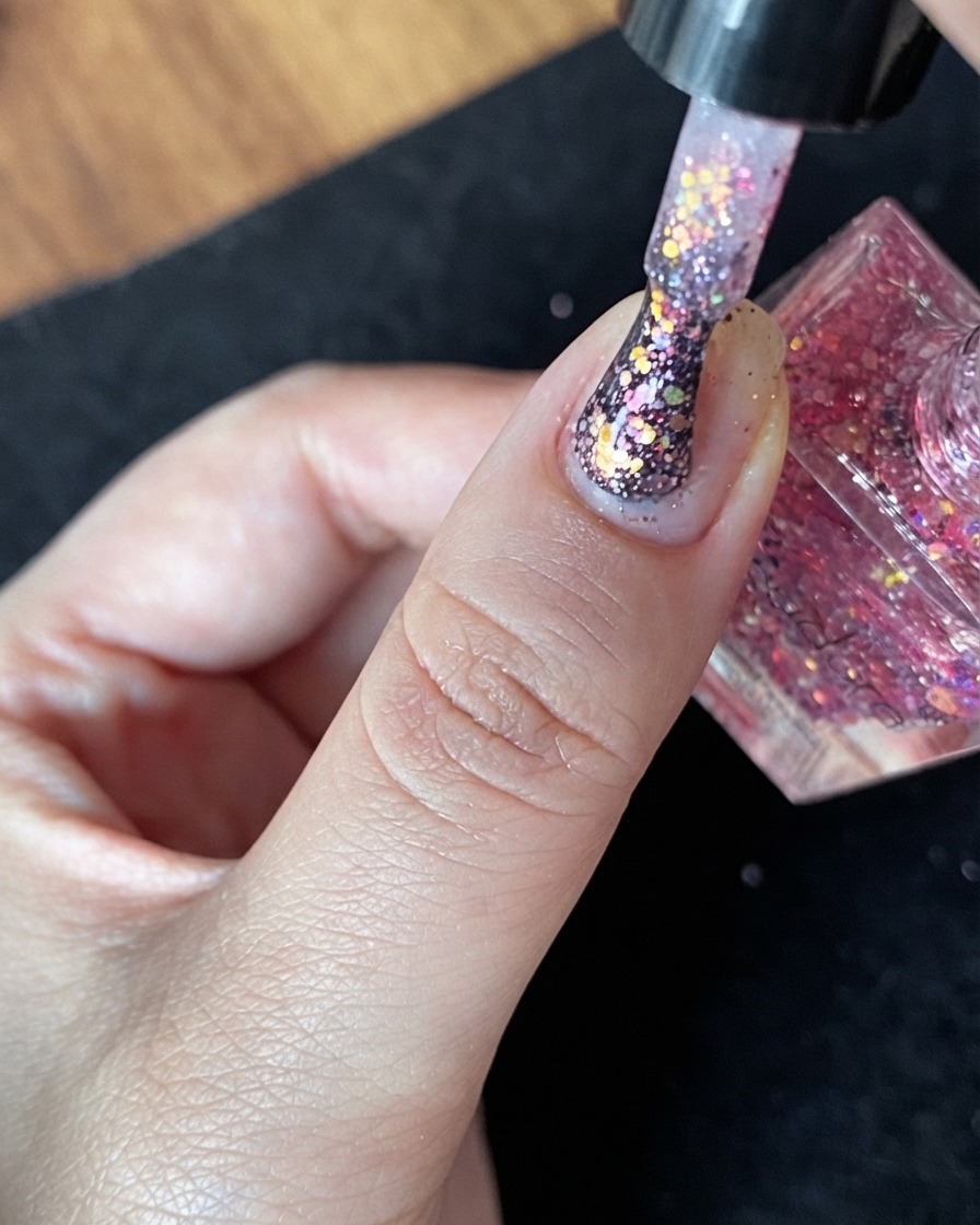 Vue rapprochée dun ongle naturel doté dune base nude et de quelques paillettes éparpillées.