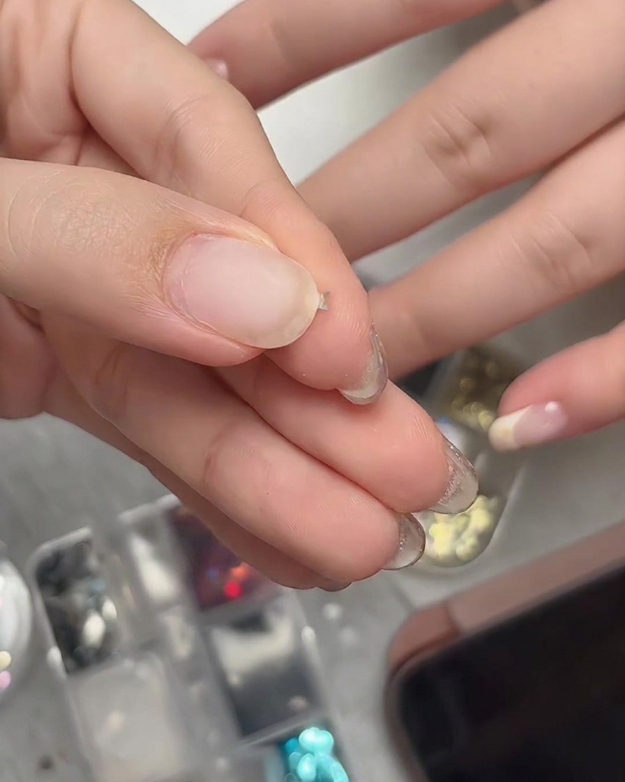 Des doigts pinçant délicatement une minuscule paillette en forme détoile pour la courber en une forme tridimensionnelle.