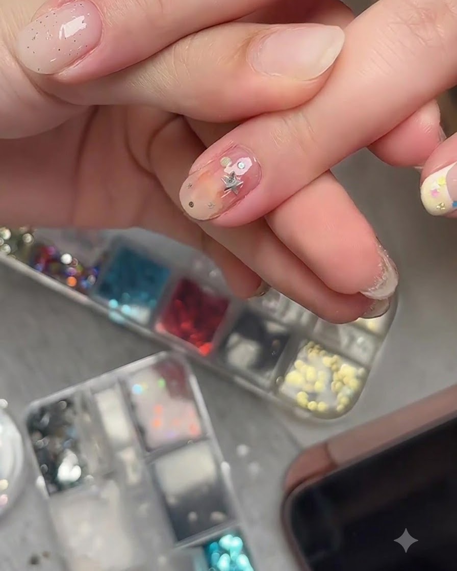 Un pinceau de nail art appliquant un top coat transparent sur des morceaux de paillettes détoiles incrustées sur un ongle fini.