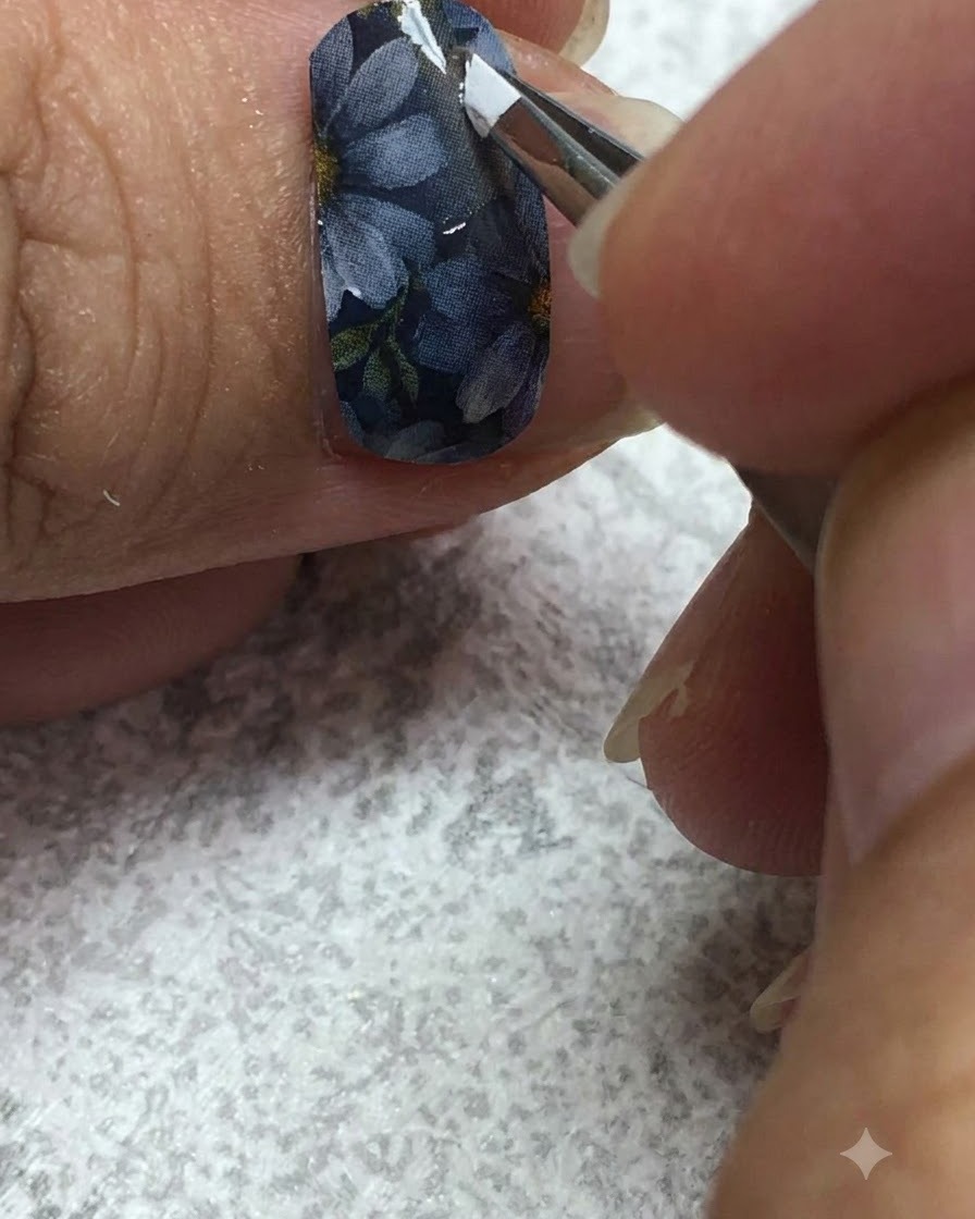Un pinceau liner fin appliquant soigneusement du gel blanc sur les pétales dune marguerite sur un ongle gris.