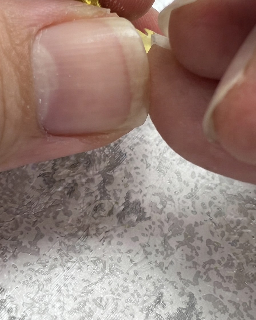 Un pinceau à ongles dessinant un trait vert vers le haut pour créer une forme de feuille à côté dune marguerite.