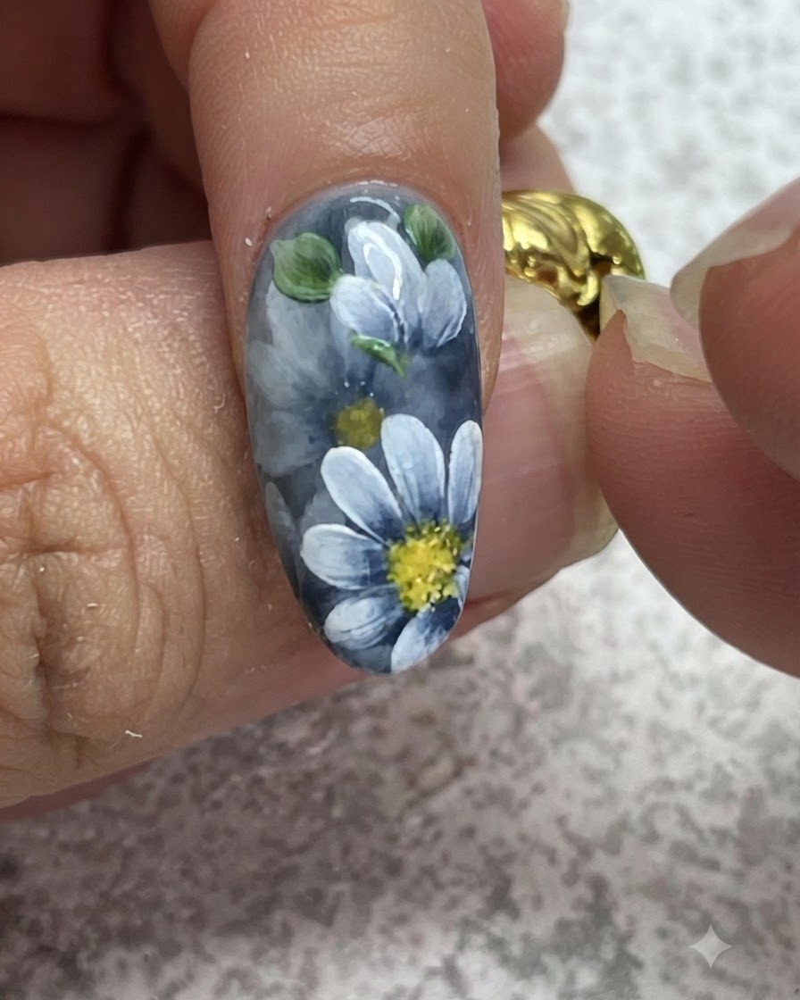 Un pinceau fin ajoutant des reflets détaillés sur des feuilles vertes peintes sur une manucure en gel gris.
