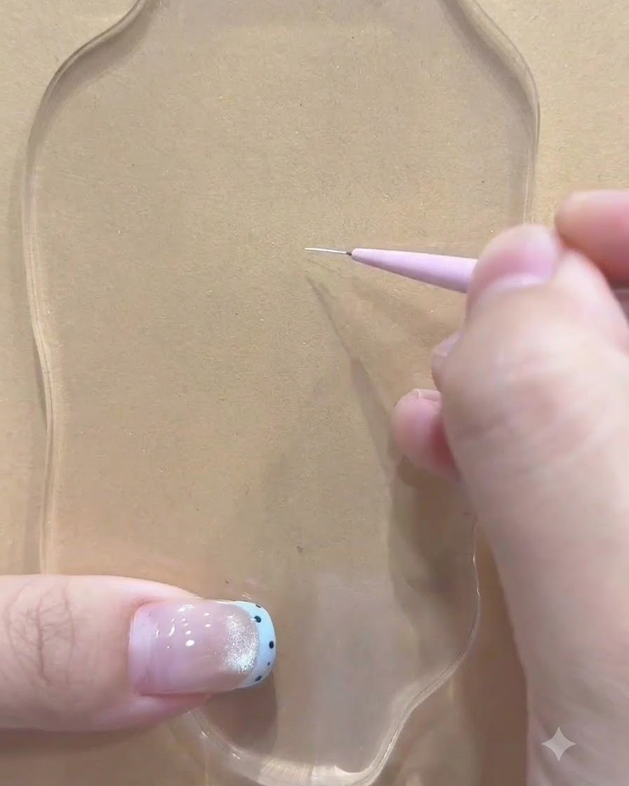 Un pinceau fin tenu par une main réalisant le premier trait blanc sur une palette transparente.