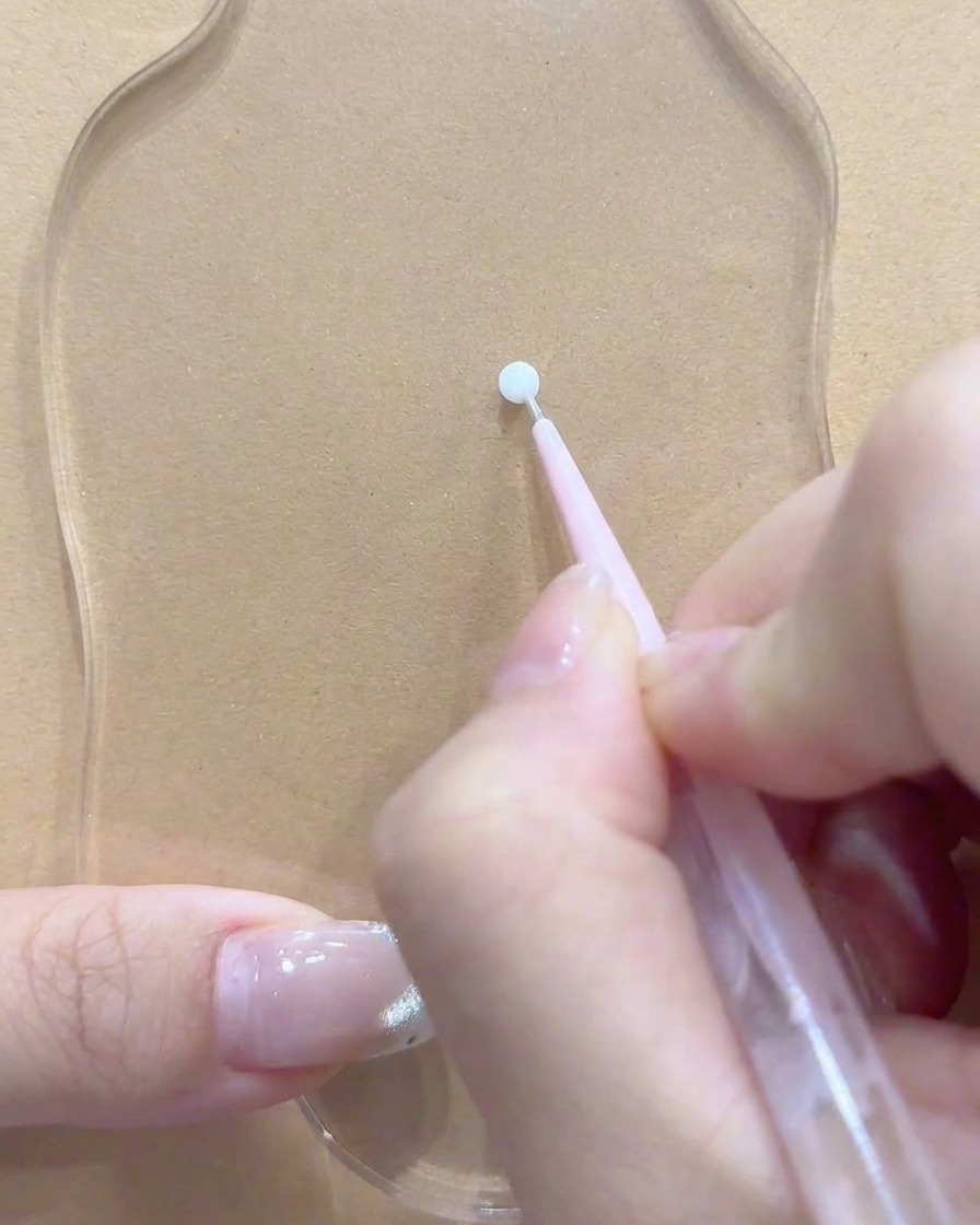 Un outil de dotting ou un pinceau posé près dun endroit propre sur la palette acrylique transparente.