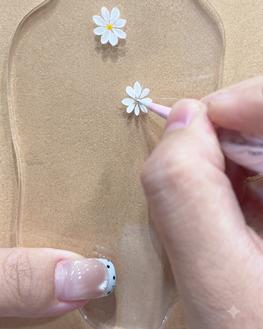 Un pinceau fin dessinant des pétales délicats pour un motif de marguerite plus petit sur une palette.