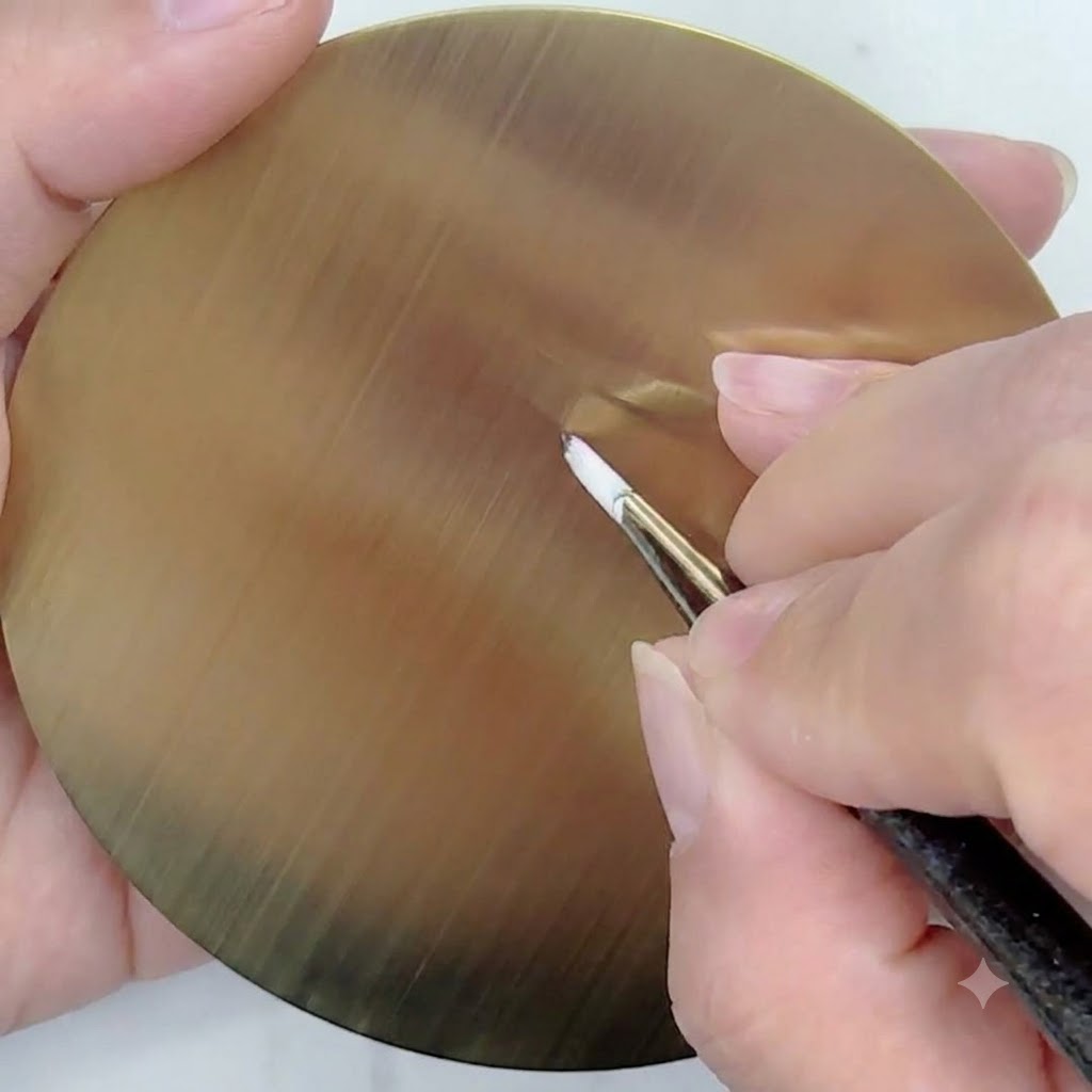 Un pinceau fin avec du gel blanc dessinant des lignes directrices droites et fines rayonnant à partir dun point central sur une palette dentraînement circulaire dorée.