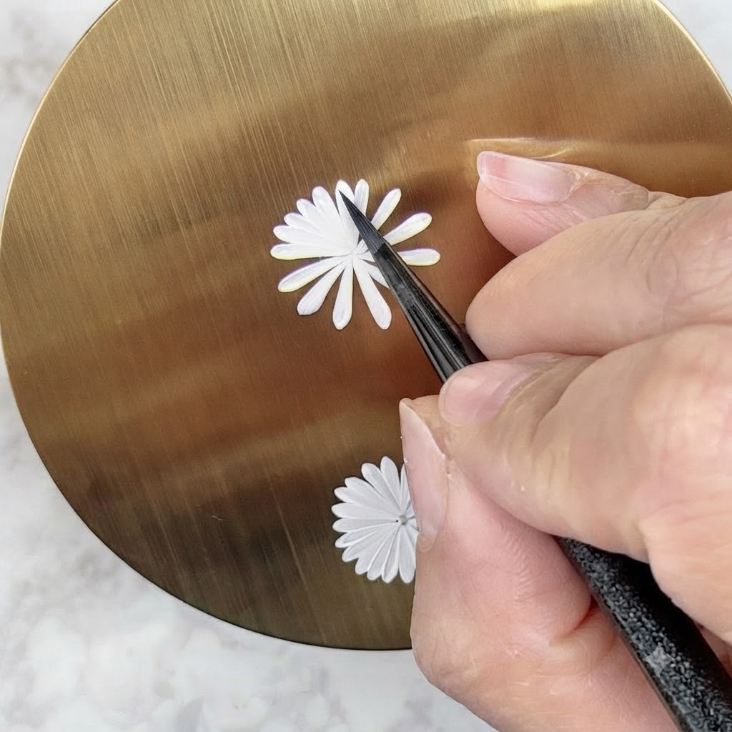 Un pinceau de nail art peignant soigneusement une deuxième couche intérieure plus petite de pétales blancs sur un motif de marguerite.
