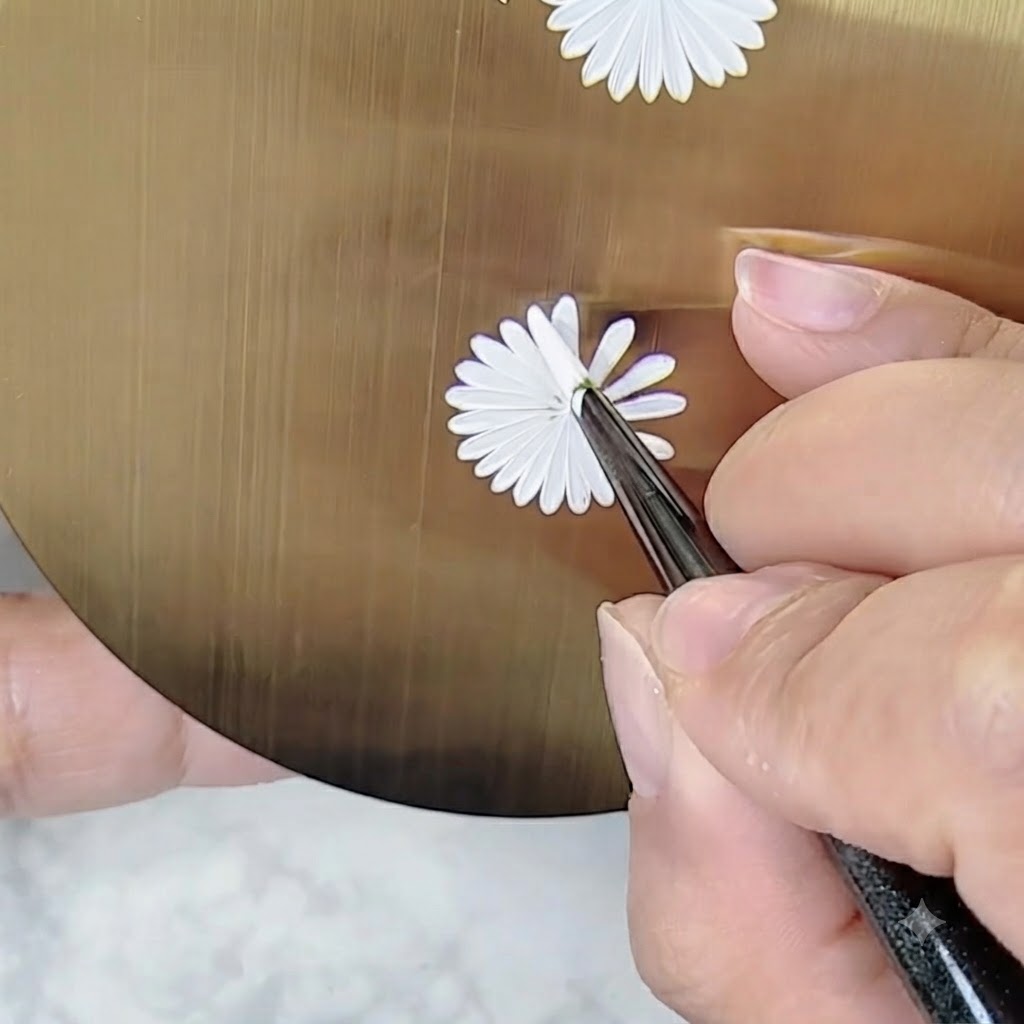 Une main tenant un pinceau de nail art à un angle ajusté pour peindre les détails sur un motif de marguerite sans tourner la palette.