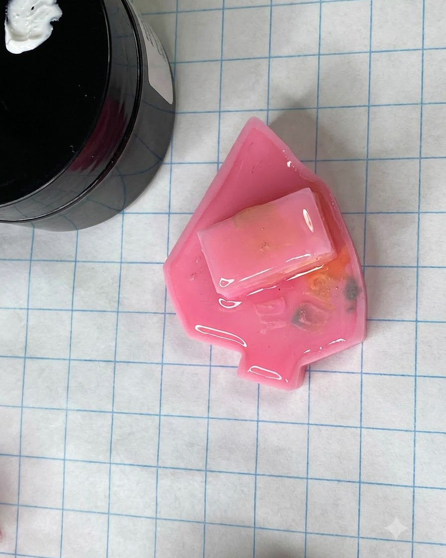 Un moule dongle rose mat catalysé reposant sur un tapis de bricolage quadrillé à côté dun pot de gel.