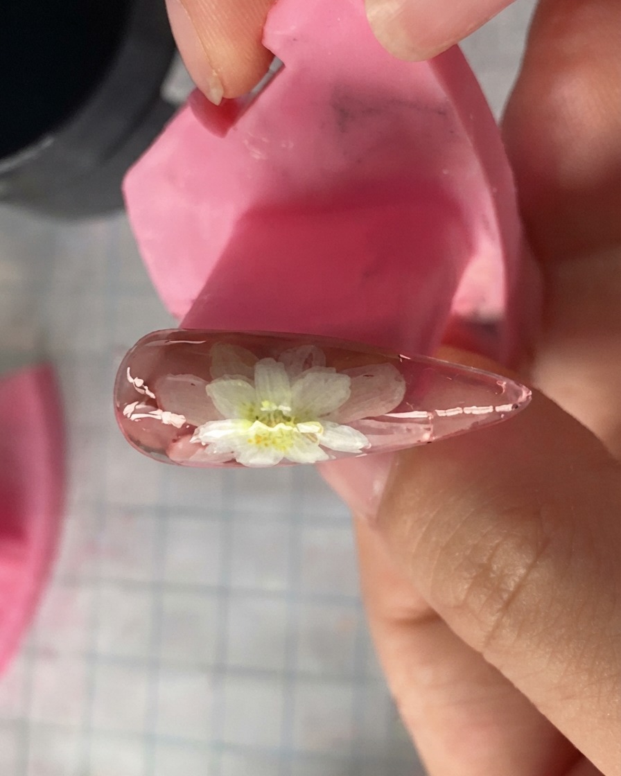 Un gros plan dun modèle dongle rose affichant des pétales de marguerite blanche superposés peints sur le dessus.