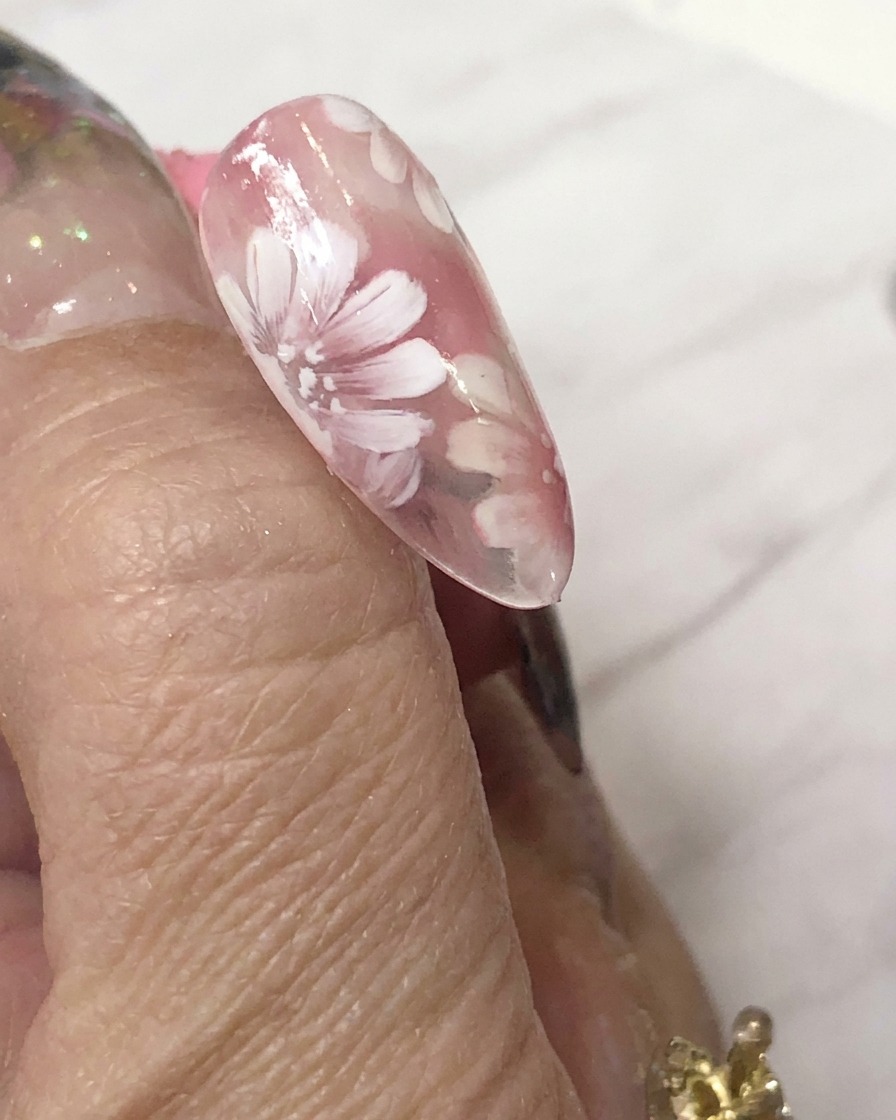 Une mini lampe de catalysation LED positionnée directement au-dessus dun ongle décoré pour catalyser le nail art en gel.