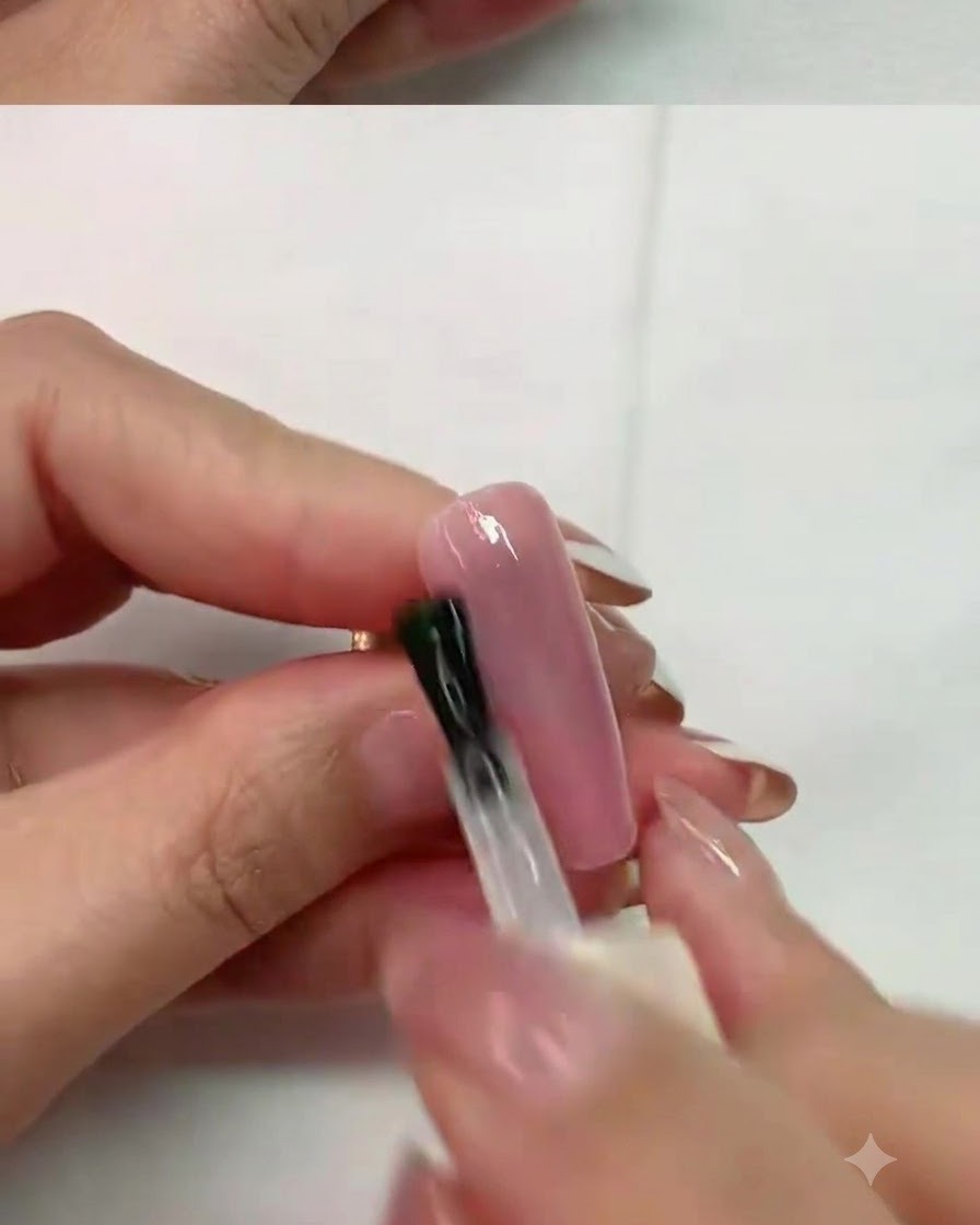 Application de catalyse au pinceau sur un ongle rose sous une lampe à ongles UV professionnelle.