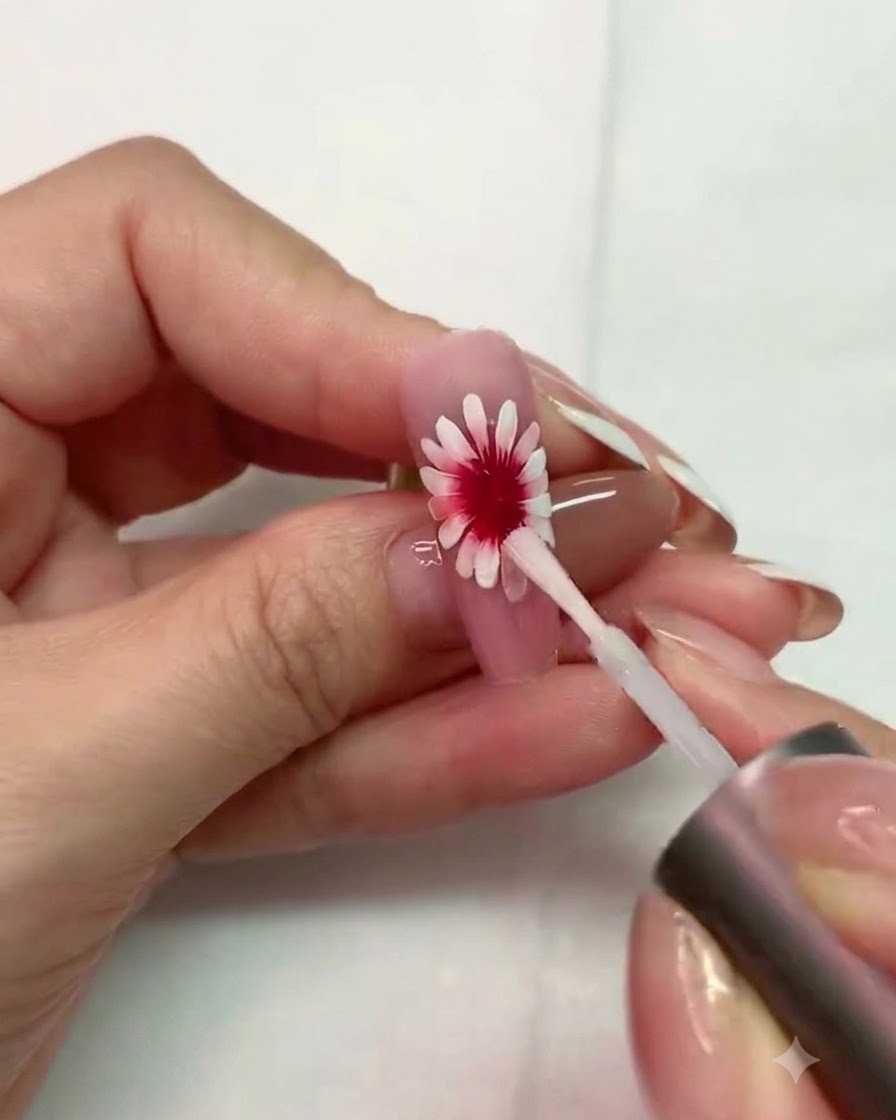 Un pinceau fin peignant une base circulaire blanche texturée avec de petits espaces au centre de la marguerite.