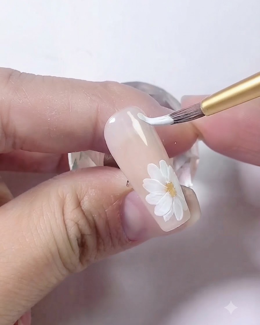 Un pinceau de nail art dessinant deux lignes blanches incurvées parallèles le long du bord de longle.