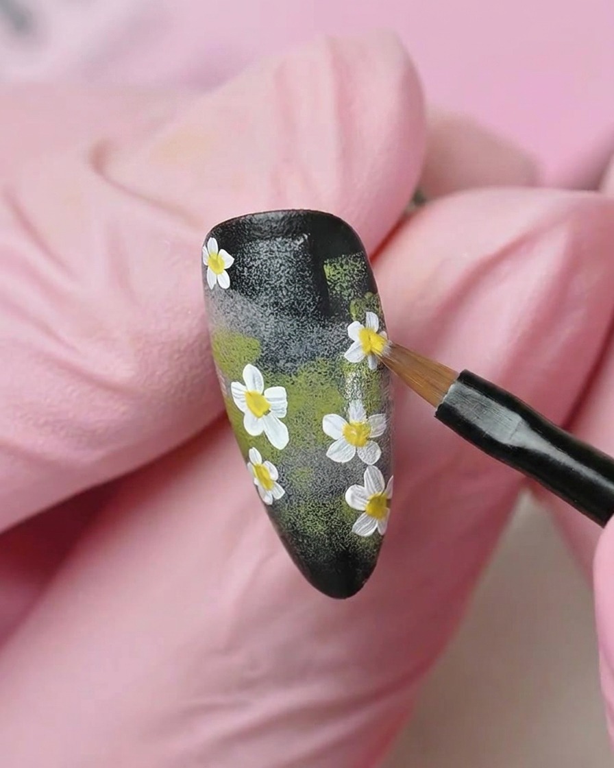 Un pinceau plat lissant une couche de vernis gel blanc laiteux translucide sur la surface de longle.