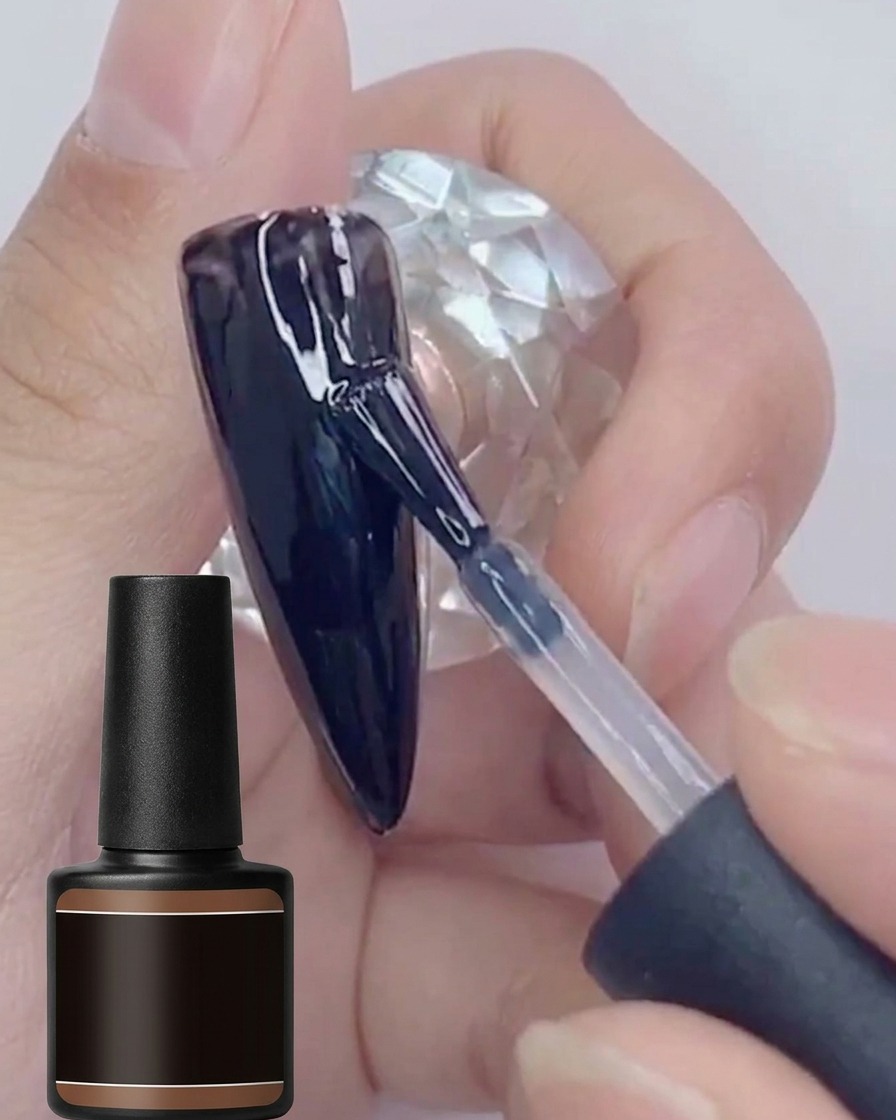 Un pinceau appliquant une seconde couche de vernis gel noir brillant sur une surface dongle déjà peinte en noir.